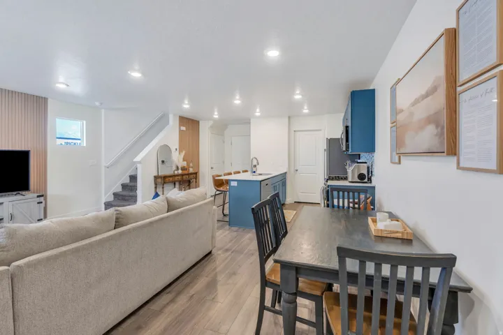 Open-concept living space featuring wood-finish flooring, recessed lighting, and a modern kitchen with blue cabinetry and a central island