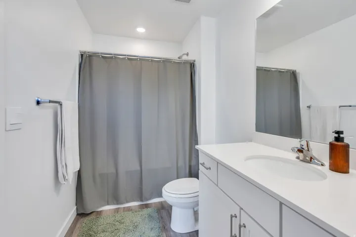 White vanity with a single basin, stainless steel faucet, and mirrored medicine cabinet