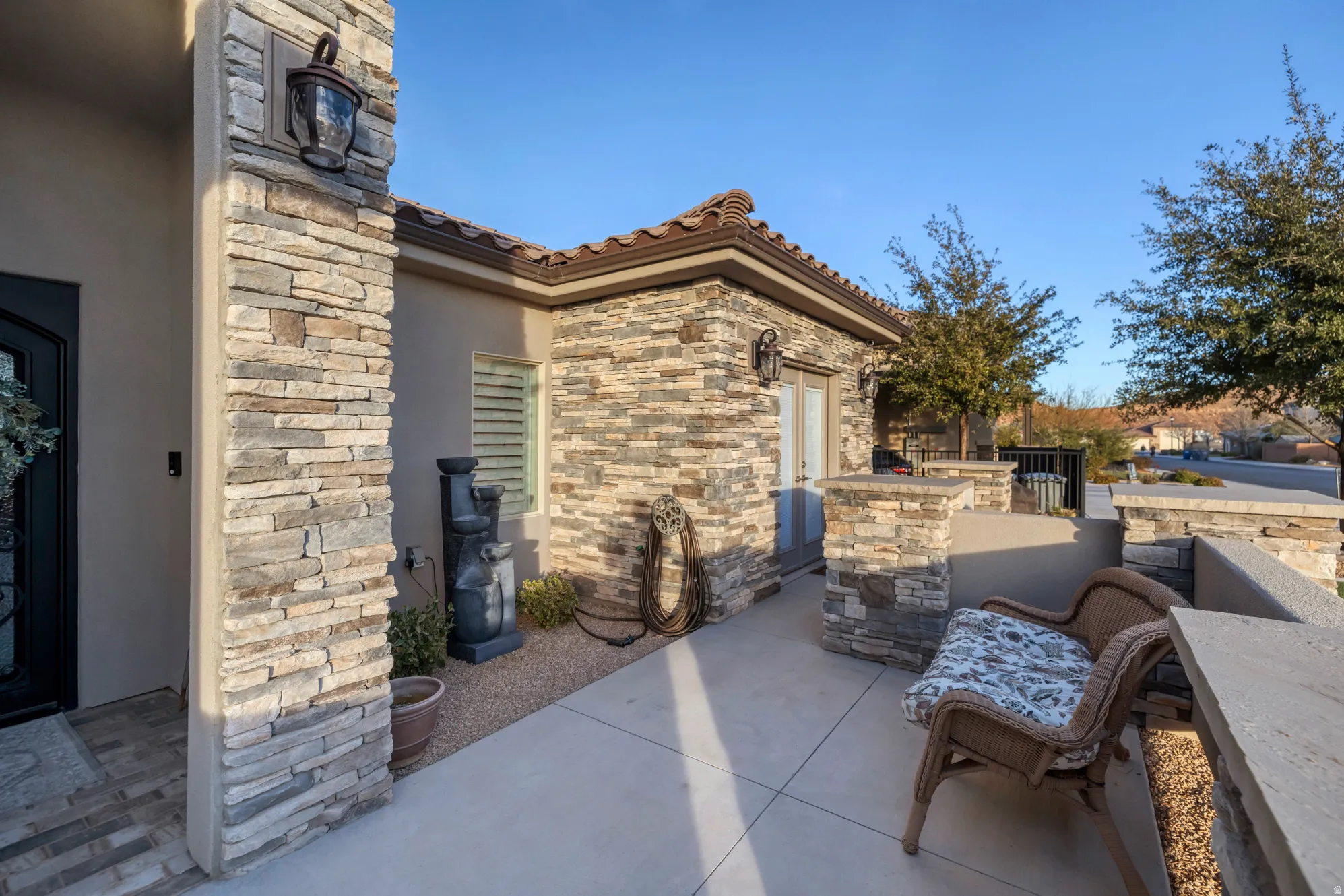 Exterior featuring stacked stone detailing, stucco finish, tile roofing, and a concrete patio