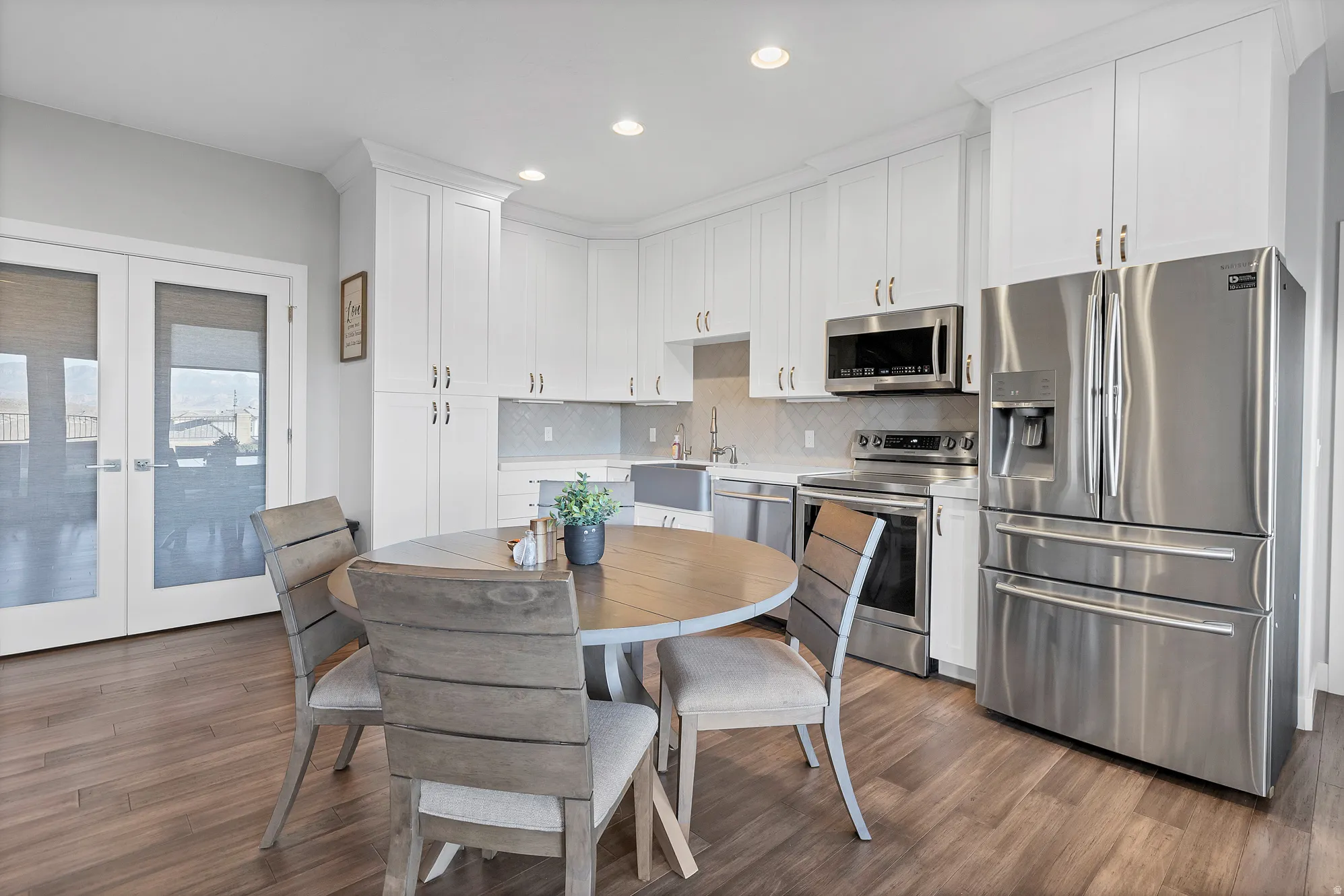 Bright kitchen featuring white cabinetry, stainless steel appliances, wood-finish flooring, and recessed lighting