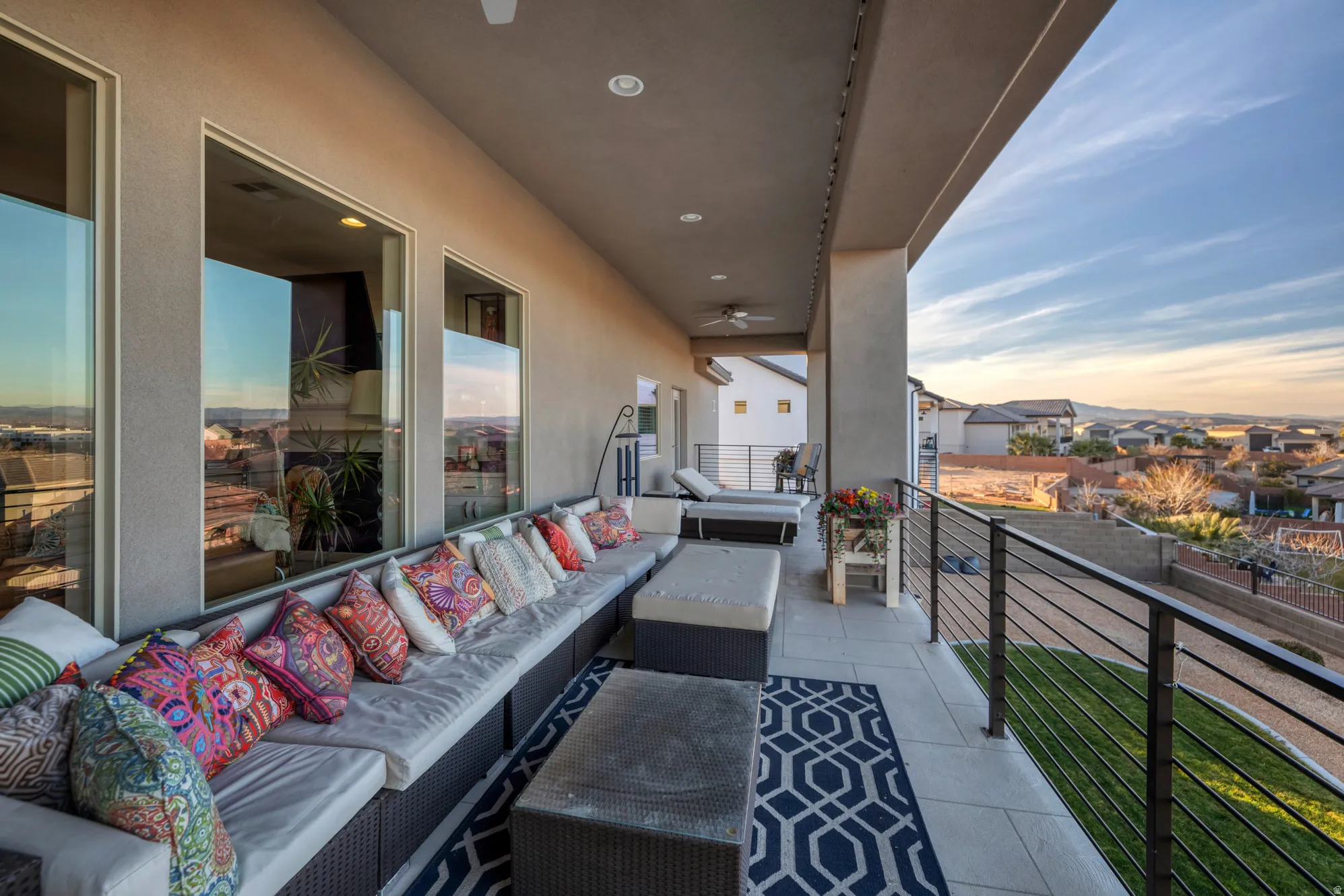 Expansive outdoor balcony with recessed lighting, ceiling fans, and a cable railing system