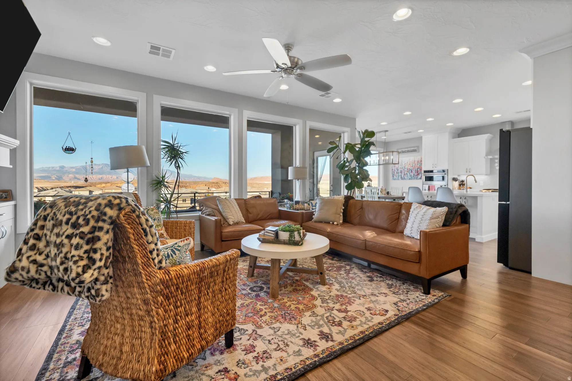 Expansive window wall, recessed lighting, ceiling fan, wood-finish flooring, and open-concept design