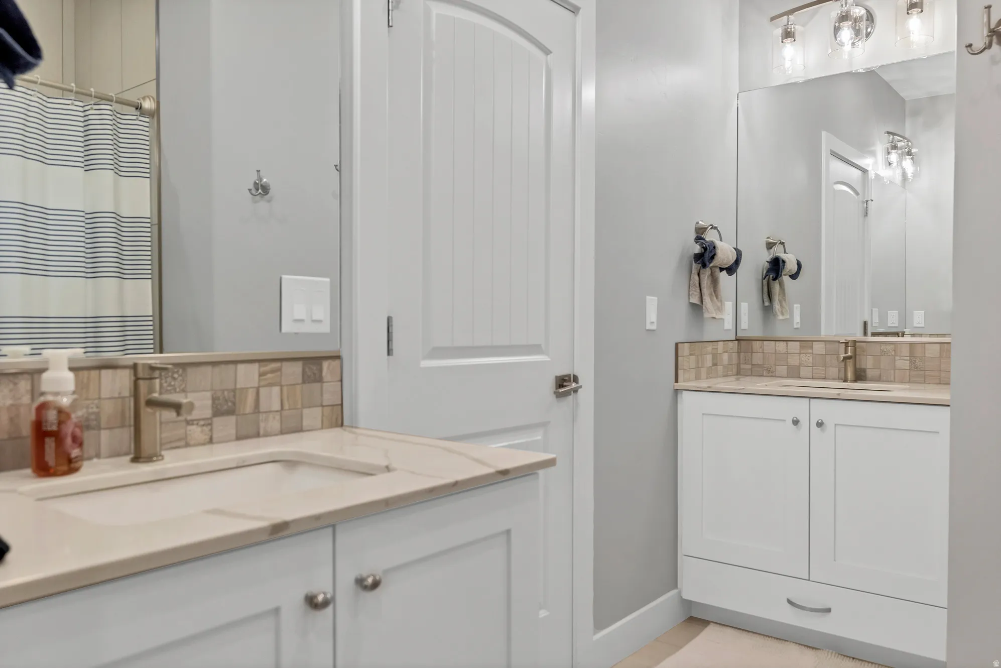 Dual vanity with integrated sinks, light-toned countertops, and mosaic tile backsplash