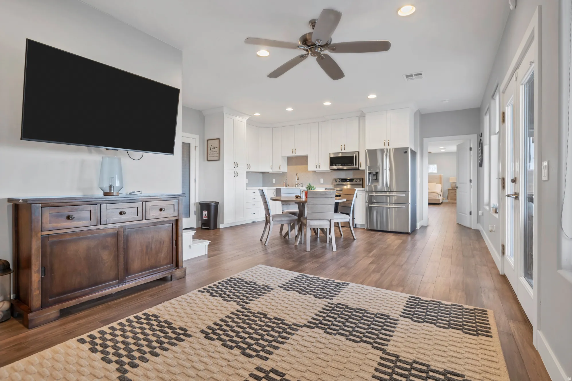 Wood-finish flooring, recessed lighting, ceiling fan, white cabinetry, and stainless steel appliances