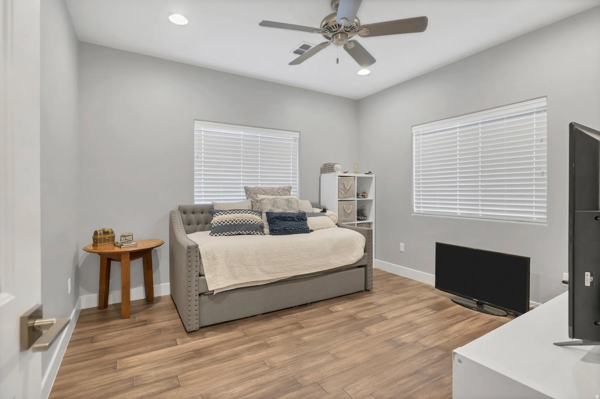 Recessed ceiling lighting, wood-finish flooring, ceiling fan with integrated lighting, window with blinds, and white baseboards