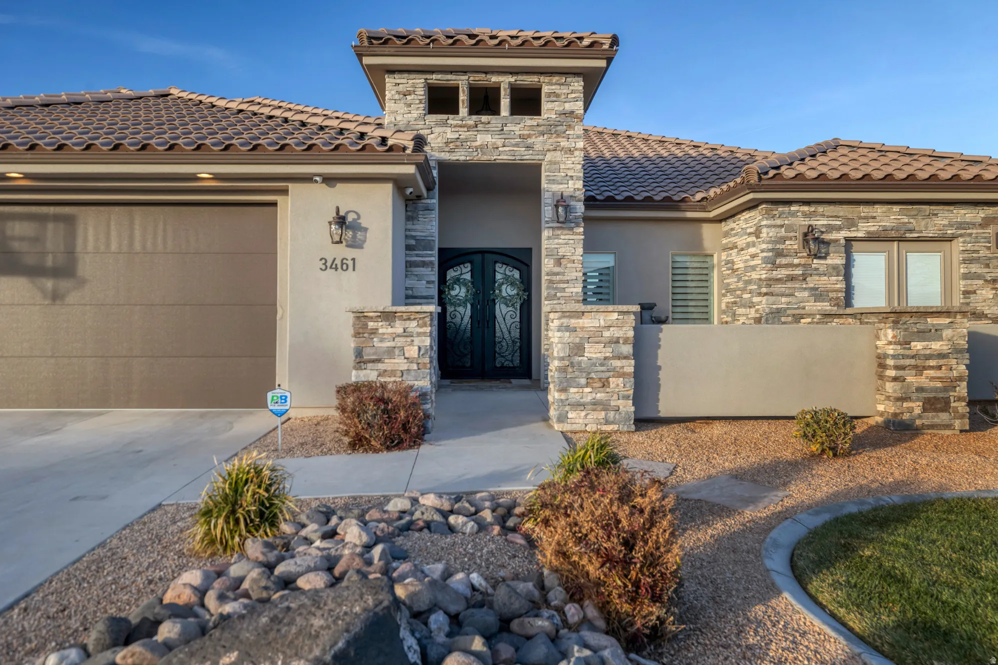 Stucco exterior with stone accents, tile roofing, and a decorative double entry door