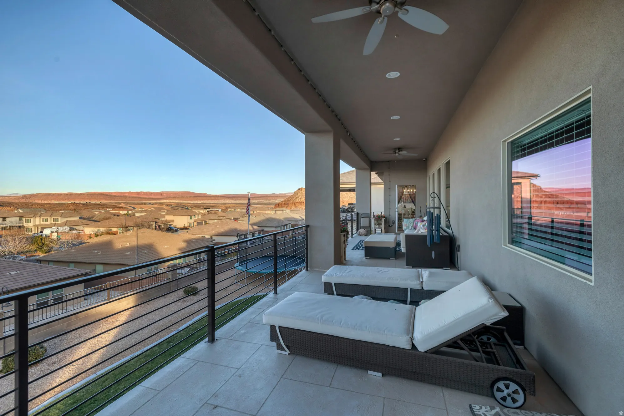 Expansive covered patio with tile flooring and a black rod iron railing