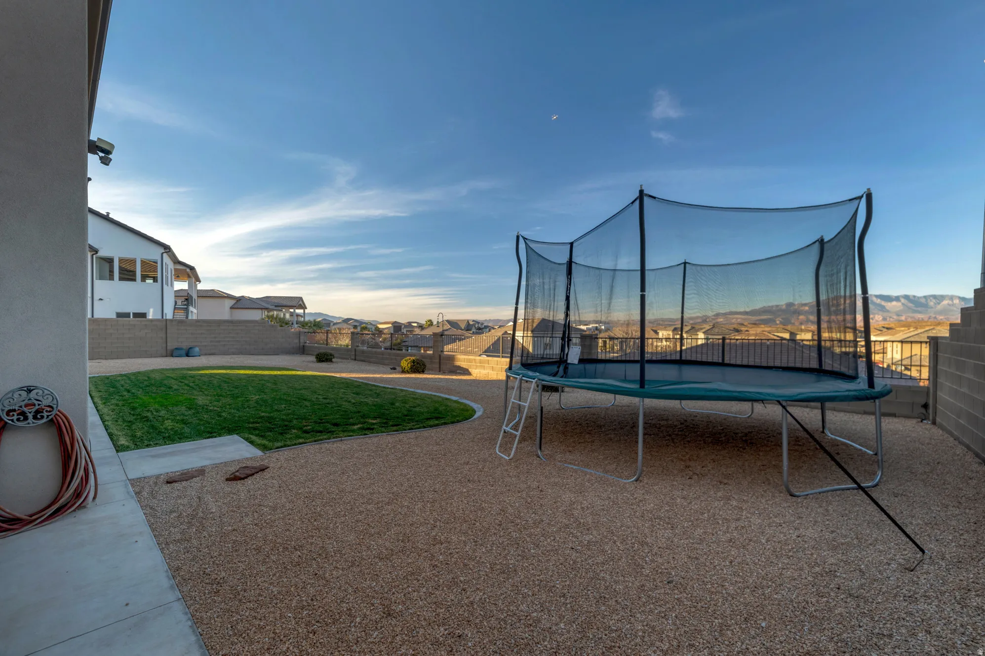 Expansive outdoor area featuring a manicured lawn, gravel landscaping, and a low-maintenance concrete block wall