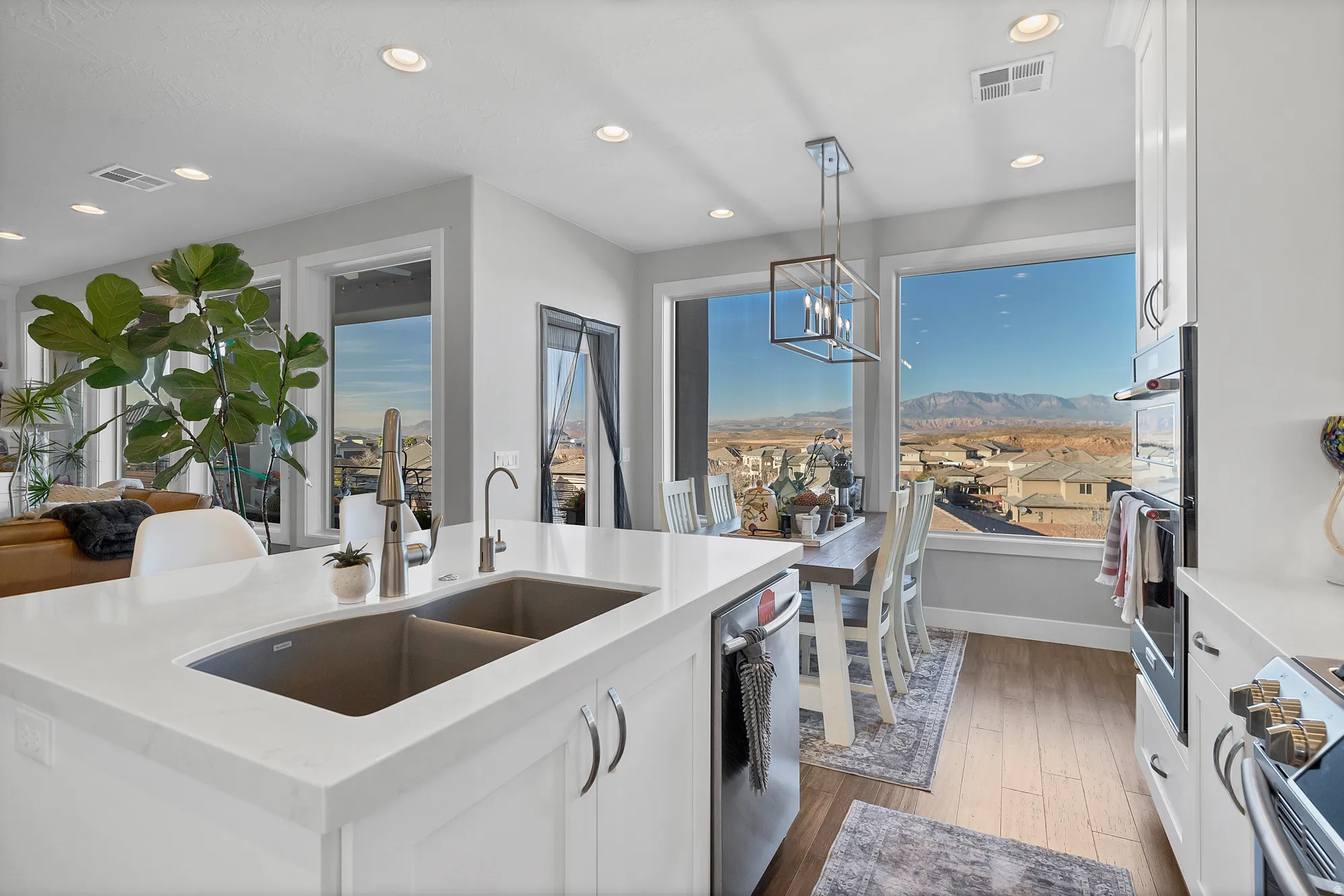 Kitchen featuring a double basin sink, light-toned cabinetry, light-toned countertops, and integrated appliances
