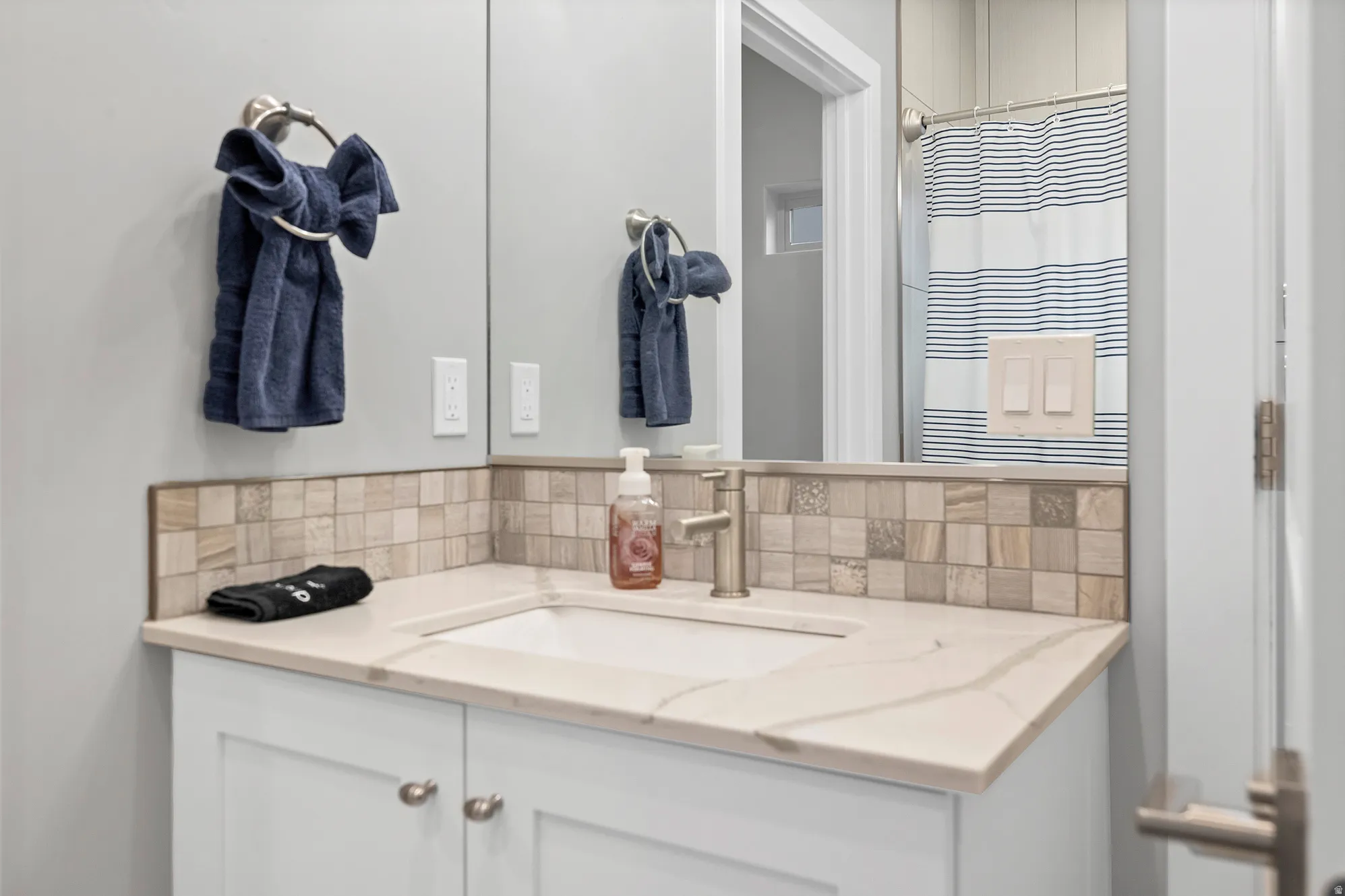 White vanity with dual cabinet doors, integrated rectangular sink, and a light-toned countertop
