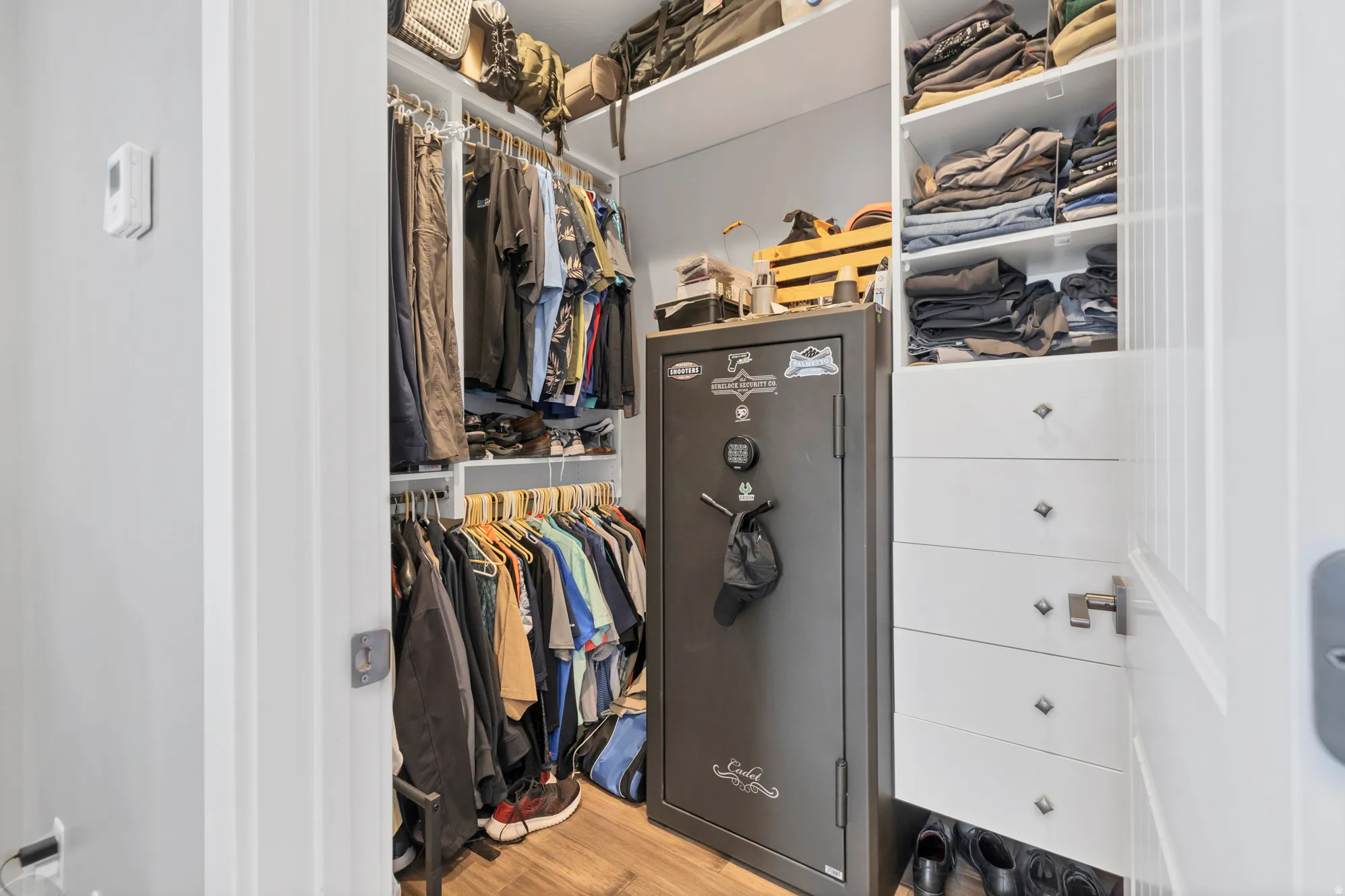 Custom closet organization system with integrated shelving, multiple hanging rods, and built-in drawers featuring decorative pulls