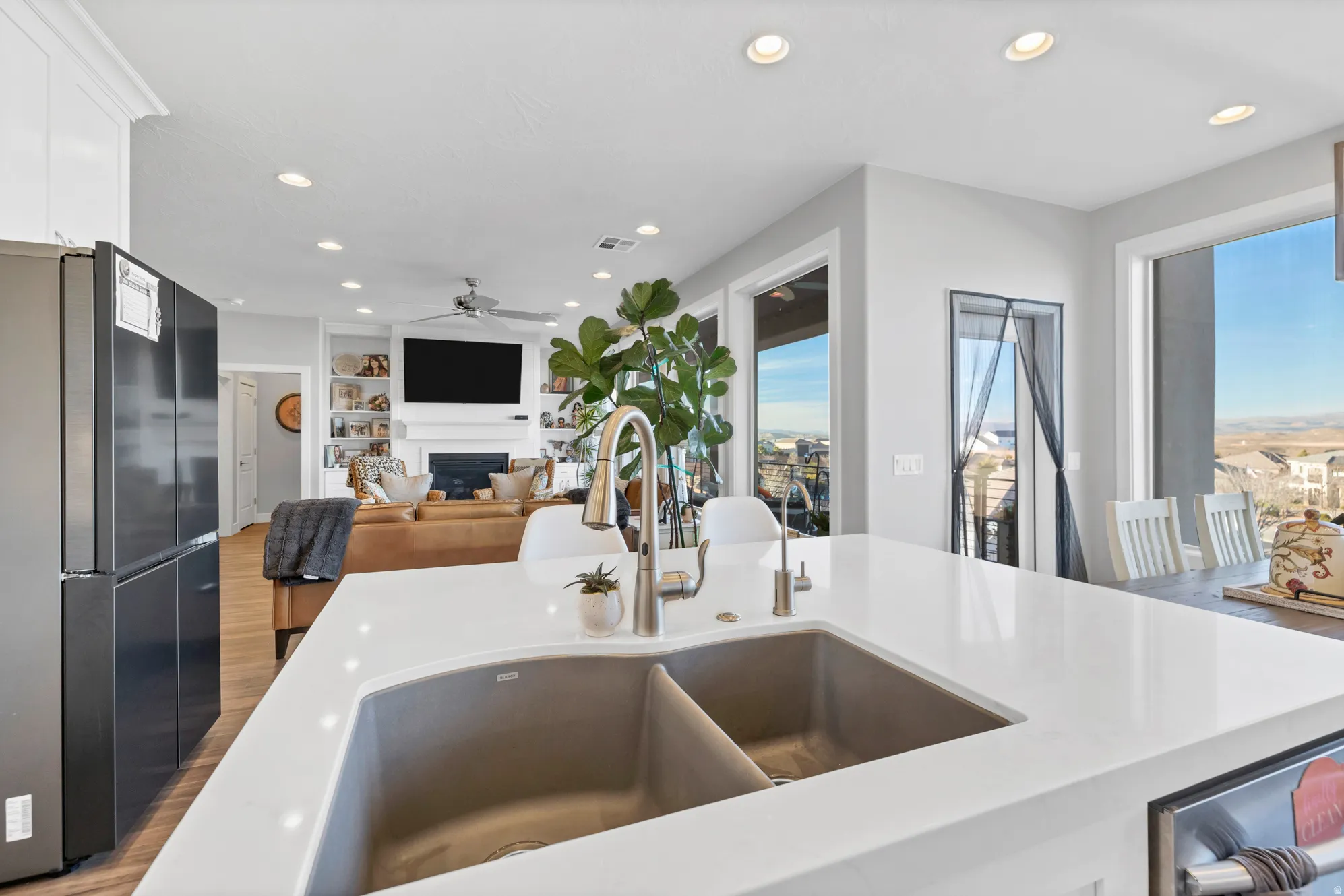 Kitchen island featuring a dual-basin sink with a gooseneck faucet, light-toned countertop, and integrated beverage cooler