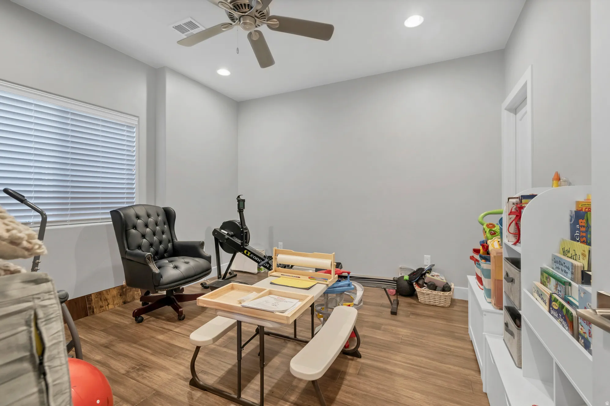 Wood-finish flooring, ceiling fan, recessed lighting, window with blinds, and light gray wall paint