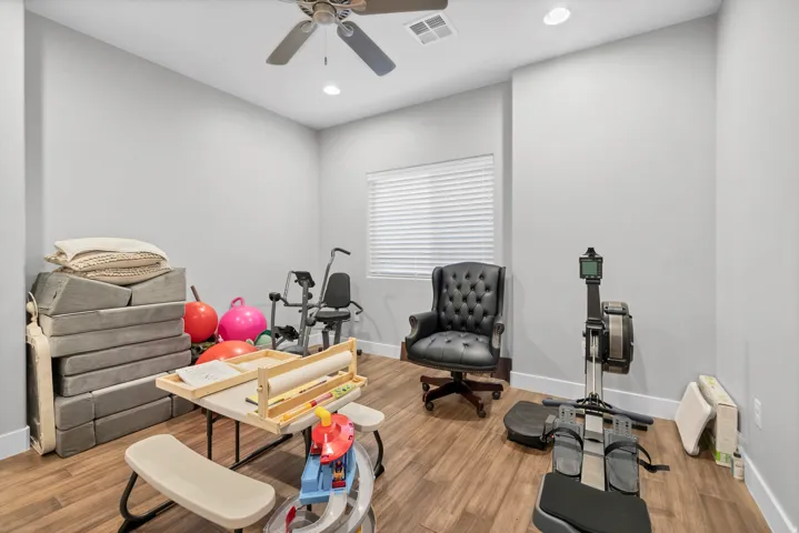Wood-finish flooring with neutral wall paint, a window with blinds, and a ceiling fan with integrated lighting