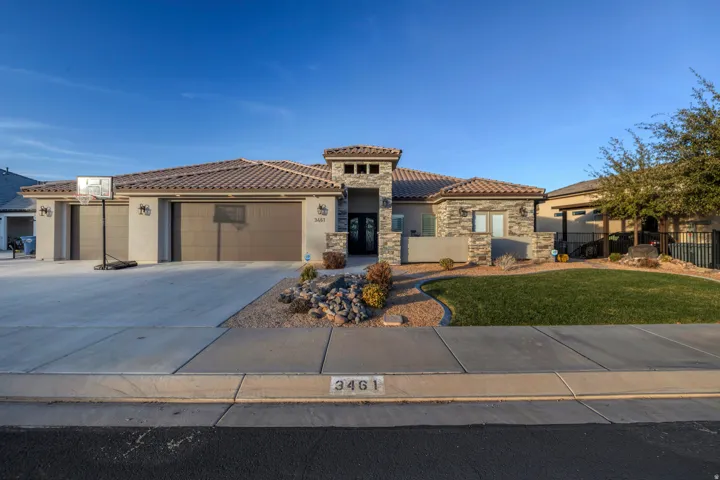 Stucco exterior with stone accents, tile roofing, and a two-car garage