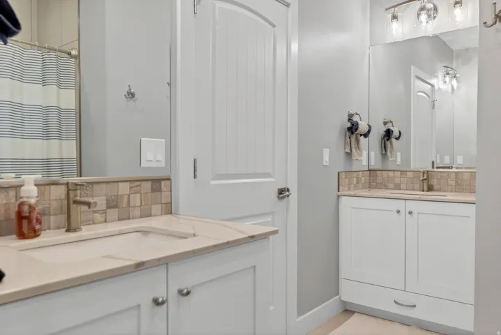 Dual vanity with integrated sinks, light-toned countertops, and mosaic tile backsplash