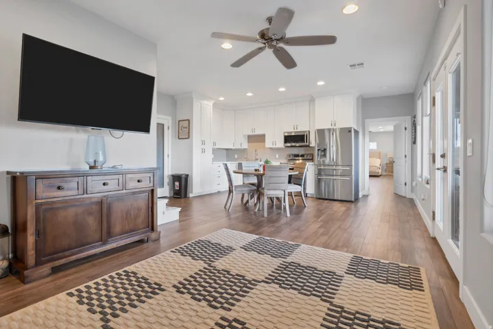 Wood-finish flooring, recessed lighting, ceiling fan, white cabinetry, and stainless steel appliances
