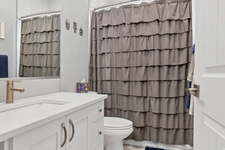 White vanity with a single basin, integrated countertop, and brass-tone faucet