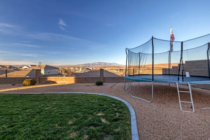 Expansive backyard featuring a manicured lawn, gravel landscaping, and a tiered block wall
