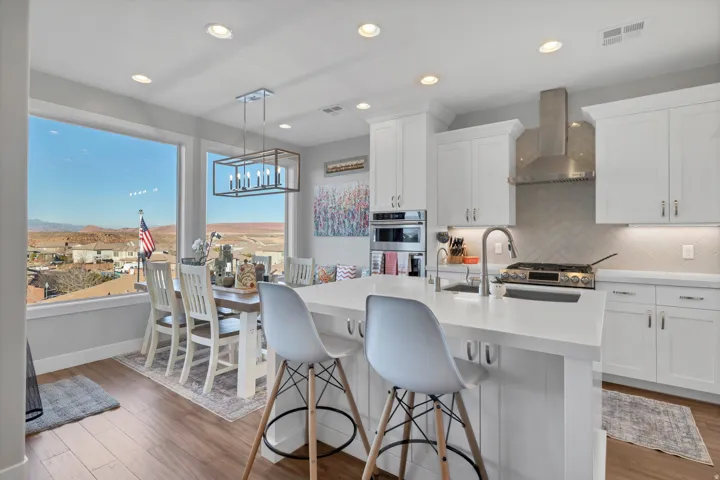 Open-concept kitchen and dining area featuring a large window, wood-finish flooring, white cabinetry, a kitchen island, and recessed lighting