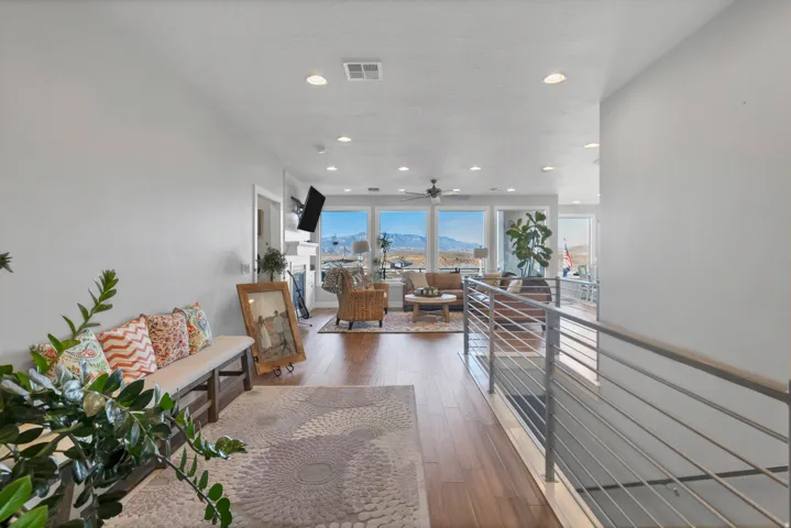 Open-concept layout with wood-finish flooring, recessed lighting, and a modern horizontal bar railing
