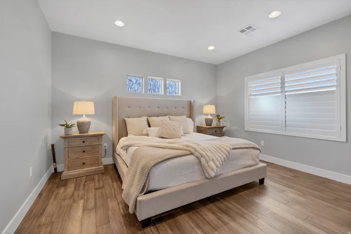 Wood-finish flooring with white baseboards, recessed lighting, and a window with plantation shutters