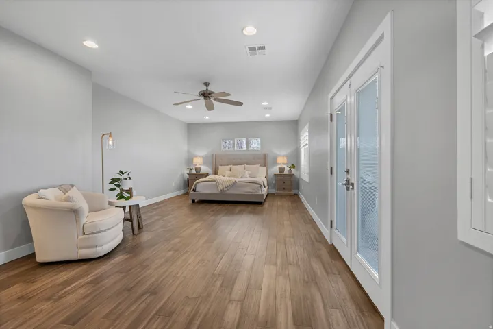 Spacious room featuring wood-finish flooring, recessed lighting, ceiling fan, and double French doors with frosted glass