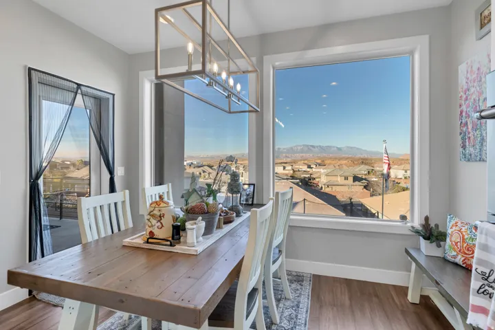 Expansive window offering a distant mountain backdrop, wood-finish flooring, and a modern rectangular chandelier