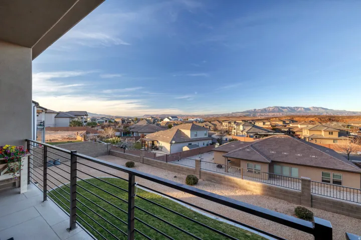 Balcony with metal railing, tile flooring, and a neighborhood backdrop with distant mountains
