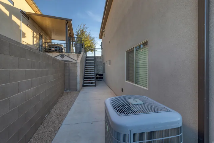 Concrete block retaining wall, covered patio structure, exterior staircase, concrete walkway, and gravel landscaping