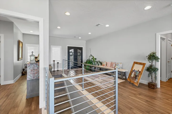 Wood-finish flooring, recessed lighting, and a modern staircase with stainless steel railings