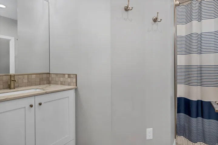 Bathroom featuring a vanity with an integrated sink, a tile backsplash, and a wall-mounted mirror