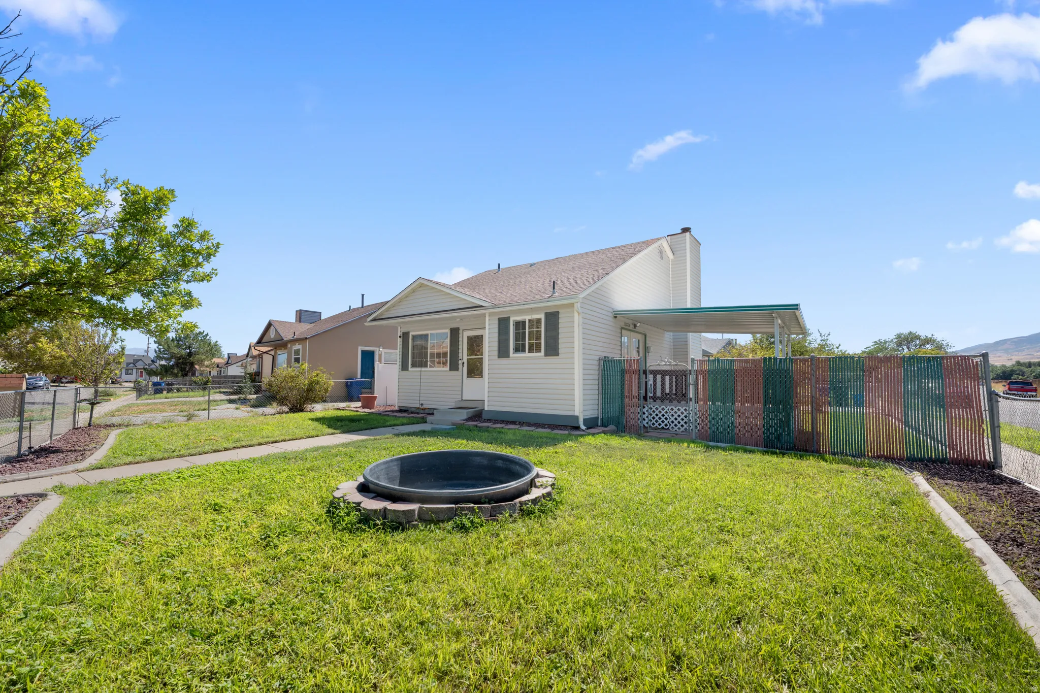 Front exterior featuring light-colored siding, a covered patio, and a fenced yard.