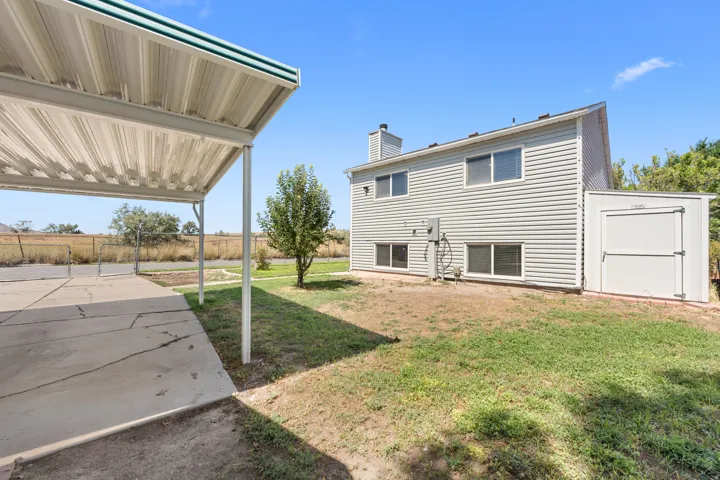 Carport with concrete pad, siding exterior, mature tree, and outdoor storage structure