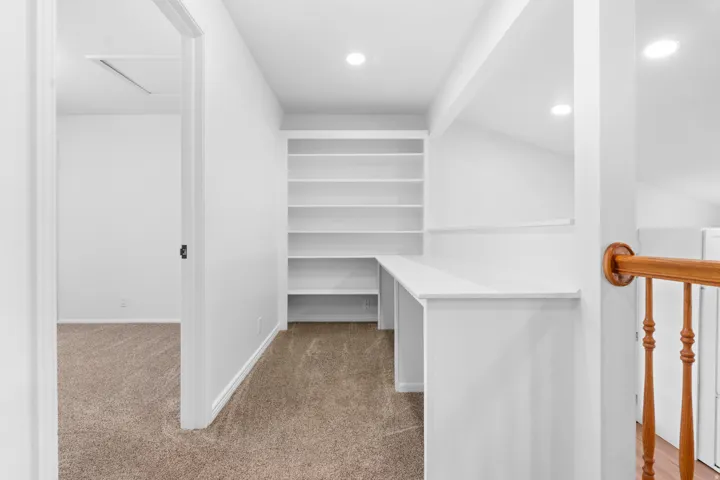 Built-in desk with shelving, recessed lighting, and carpeted flooring