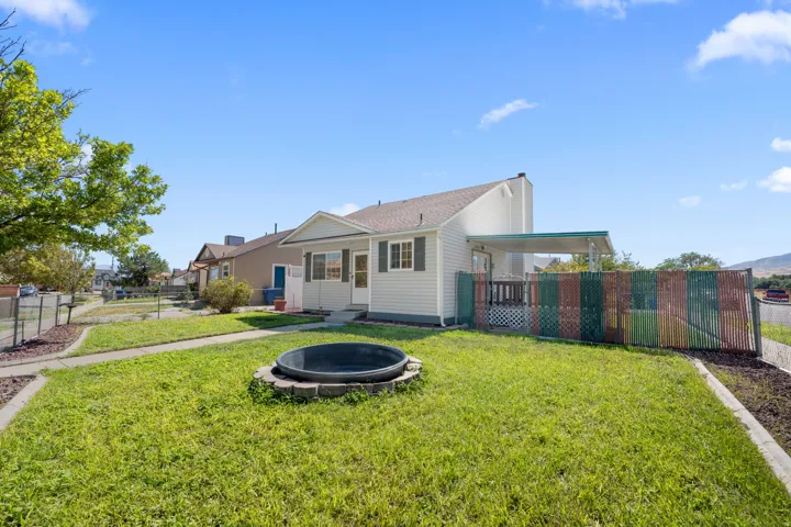 Front exterior featuring light-colored siding, a covered patio, and a fenced yard.