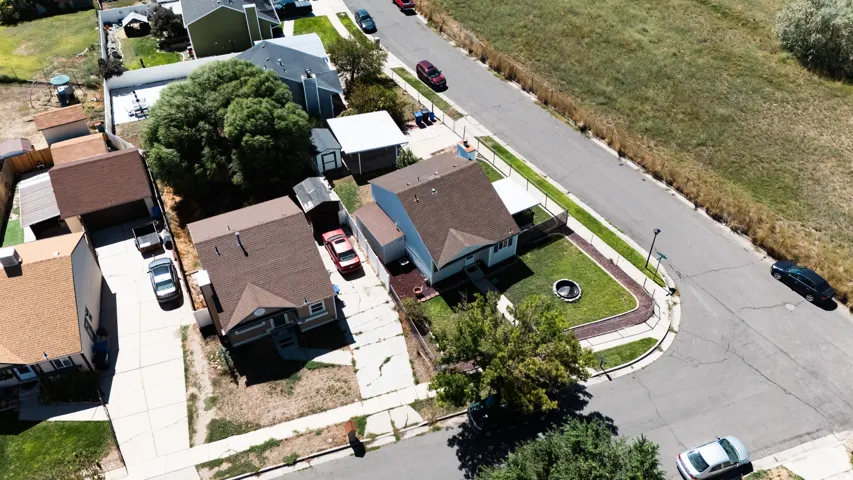 Corner lot property featuring a manicured lawn, established trees, and a concrete driveway