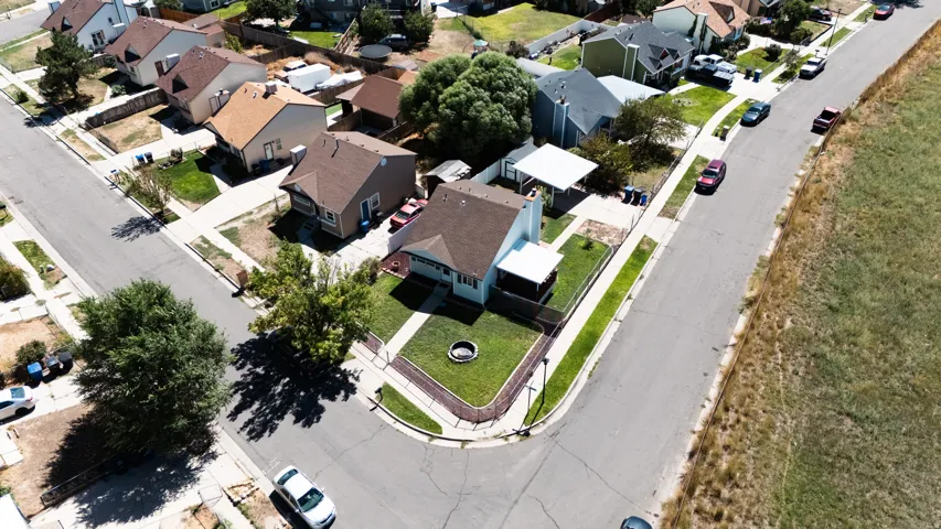 Corner lot with a manicured lawn, established trees, and a covered patio