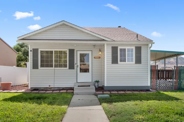 Light-colored siding exterior with dark shutters, covered front porch, and a paved walkway