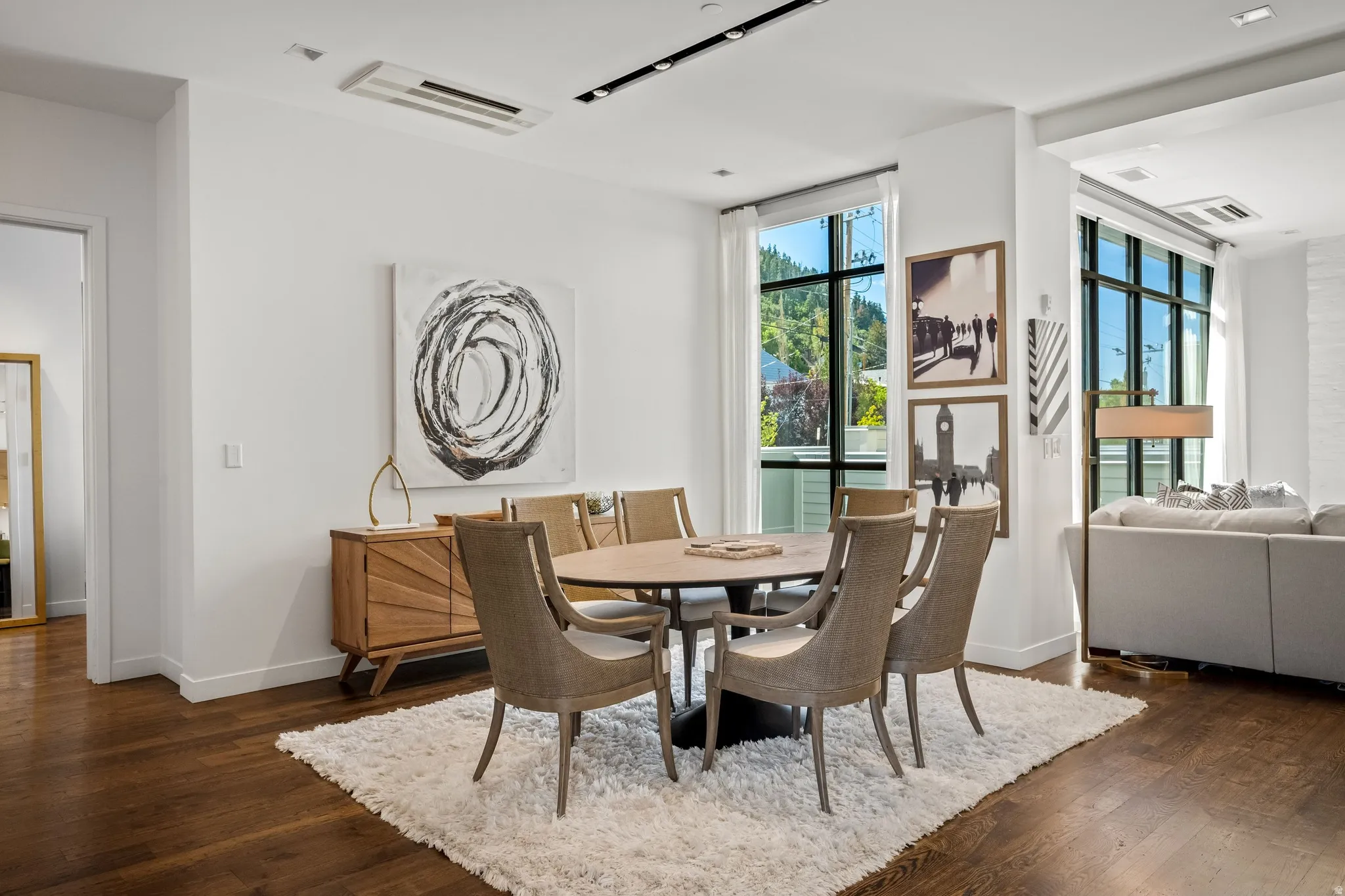 Hardwood flooring throughout, large windows with black frames, recessed lighting, and white walls