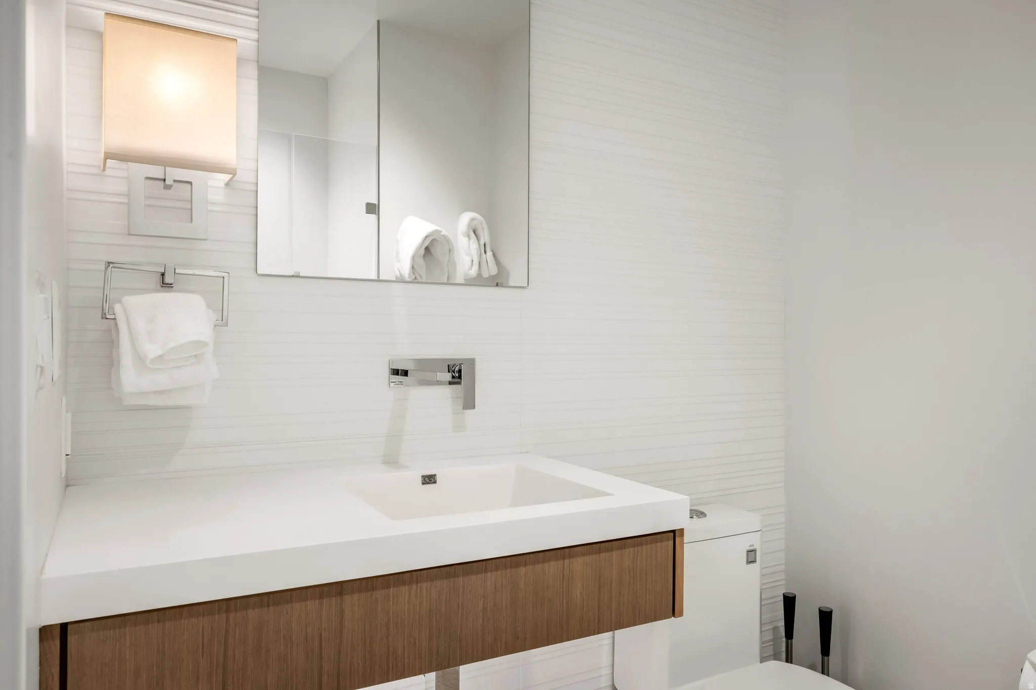 Modern vanity featuring a wood-finish cabinet, integrated basin, and chrome wall-mounted faucet