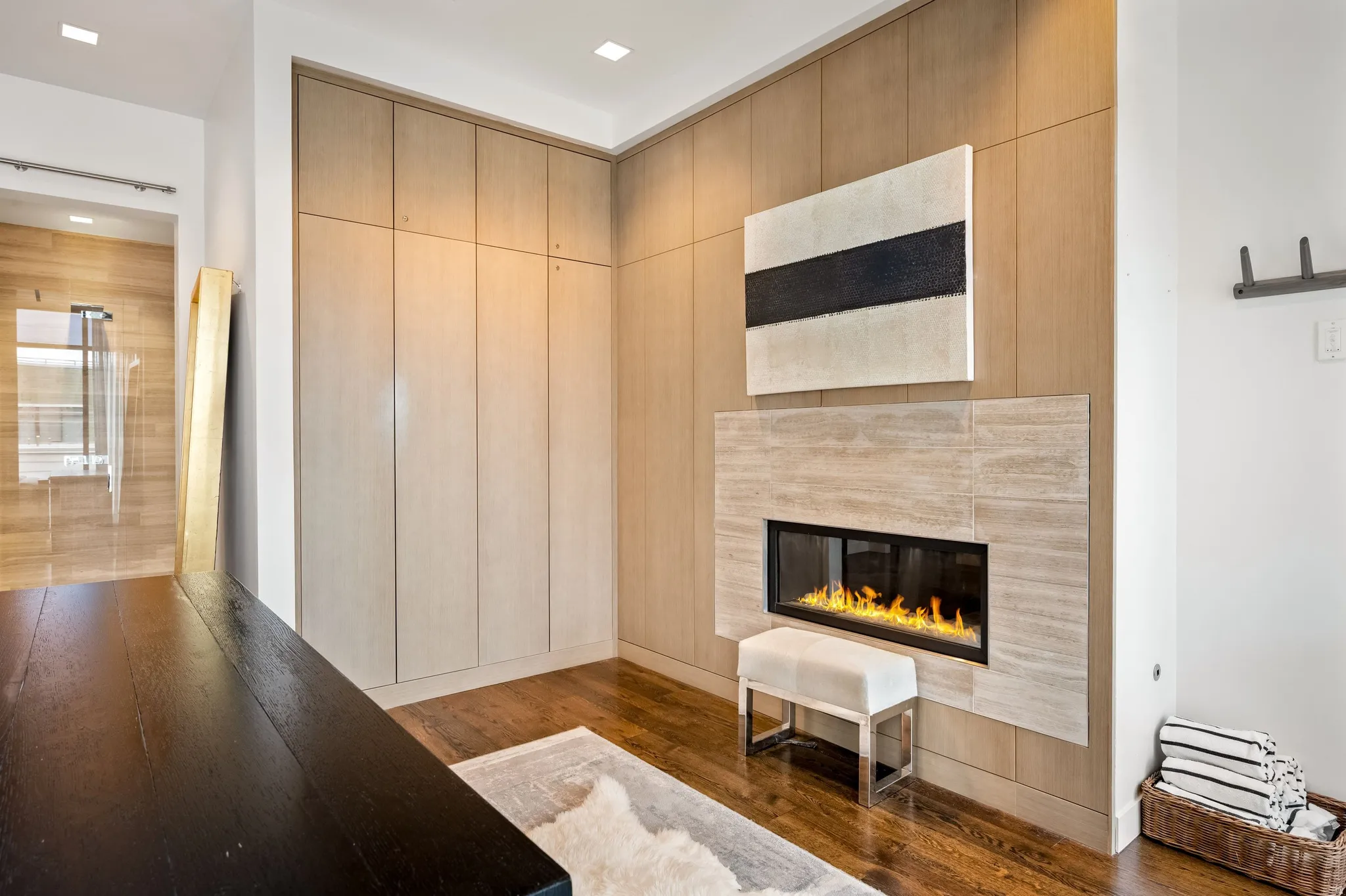 Wood-finish flooring with a linear fireplace featuring a stone surround
