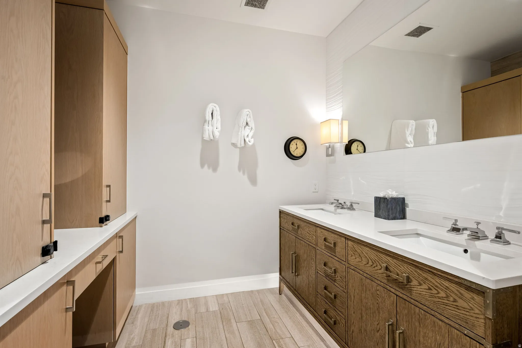 Dual vanity with integrated sinks, wood-finish cabinetry, and white countertops