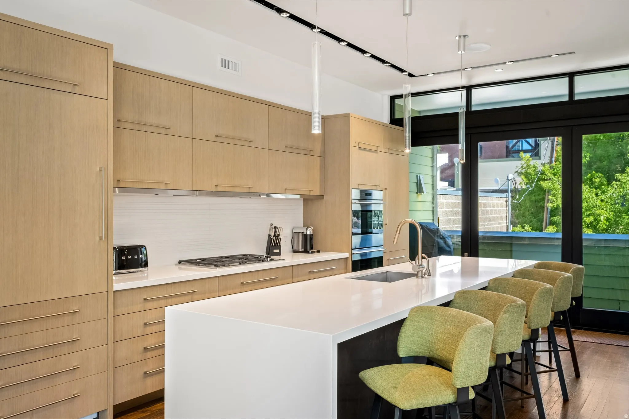 Modern kitchen featuring light wood-finish cabinetry, integrated oven, and a built-in cooktop