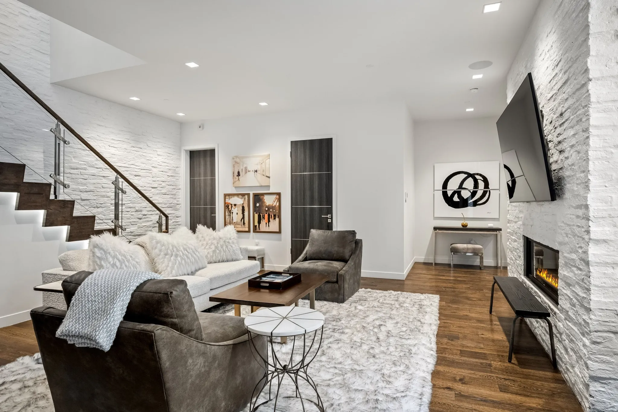 Hardwood flooring, recessed lighting, and a modern fireplace with a stone-clad surround