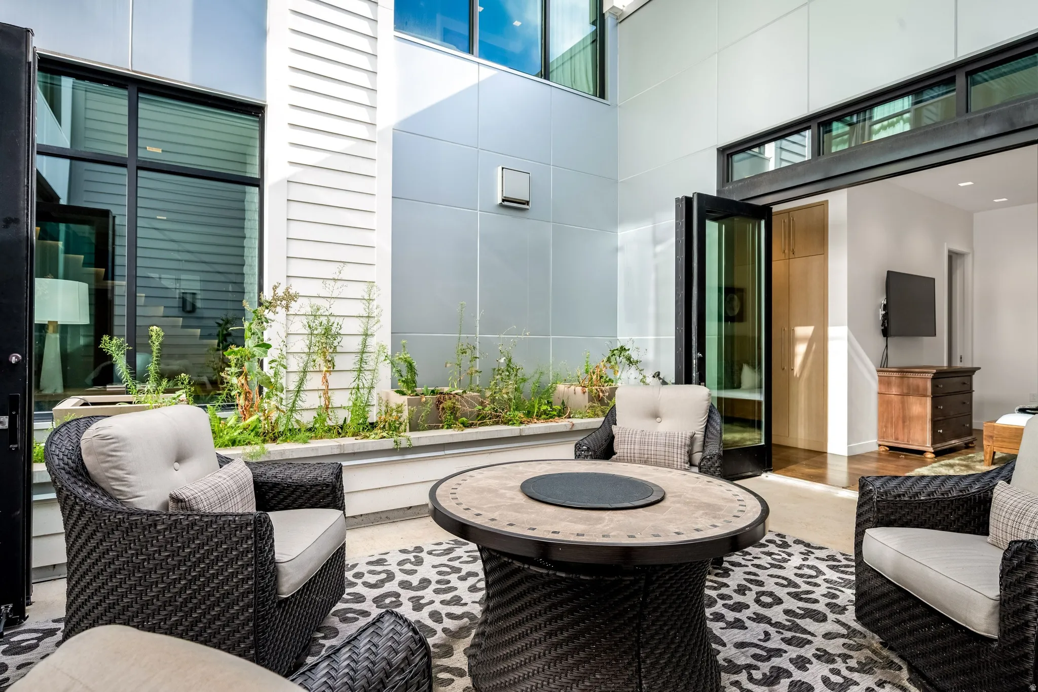Outdoor patio featuring a built-in planter, large glass panel doors, and modern exterior siding