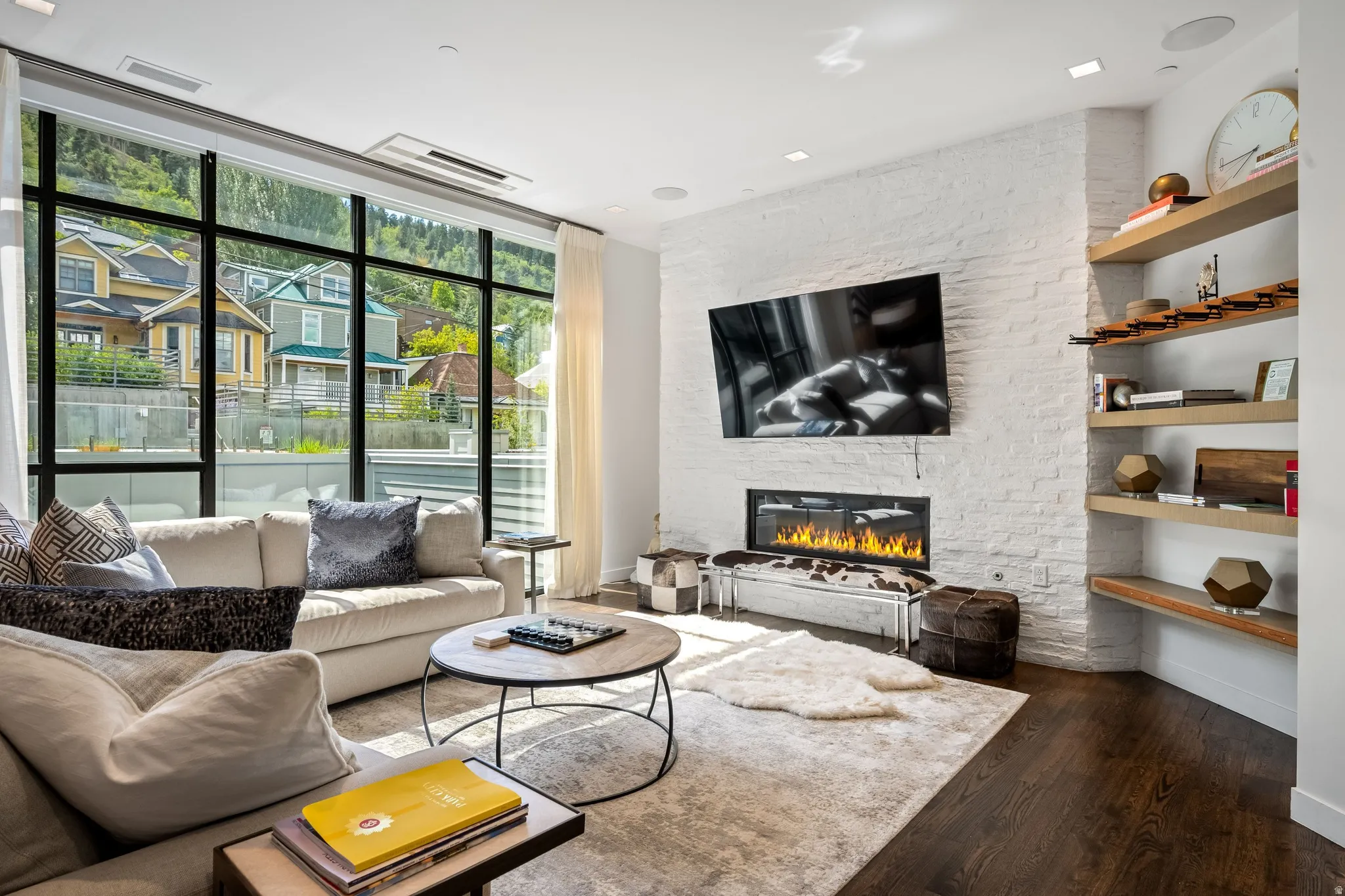 Living area featuring a full-wall window, a built-in fireplace, a white brick accent wall, recessed lighting, and dark wood-finish flooring