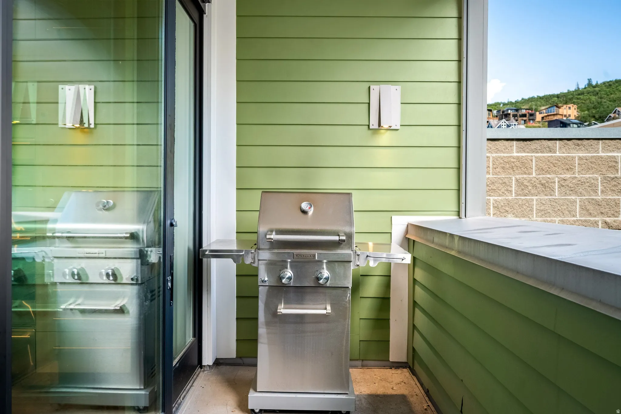 Green horizontal siding, stainless steel grill, and sliding glass door