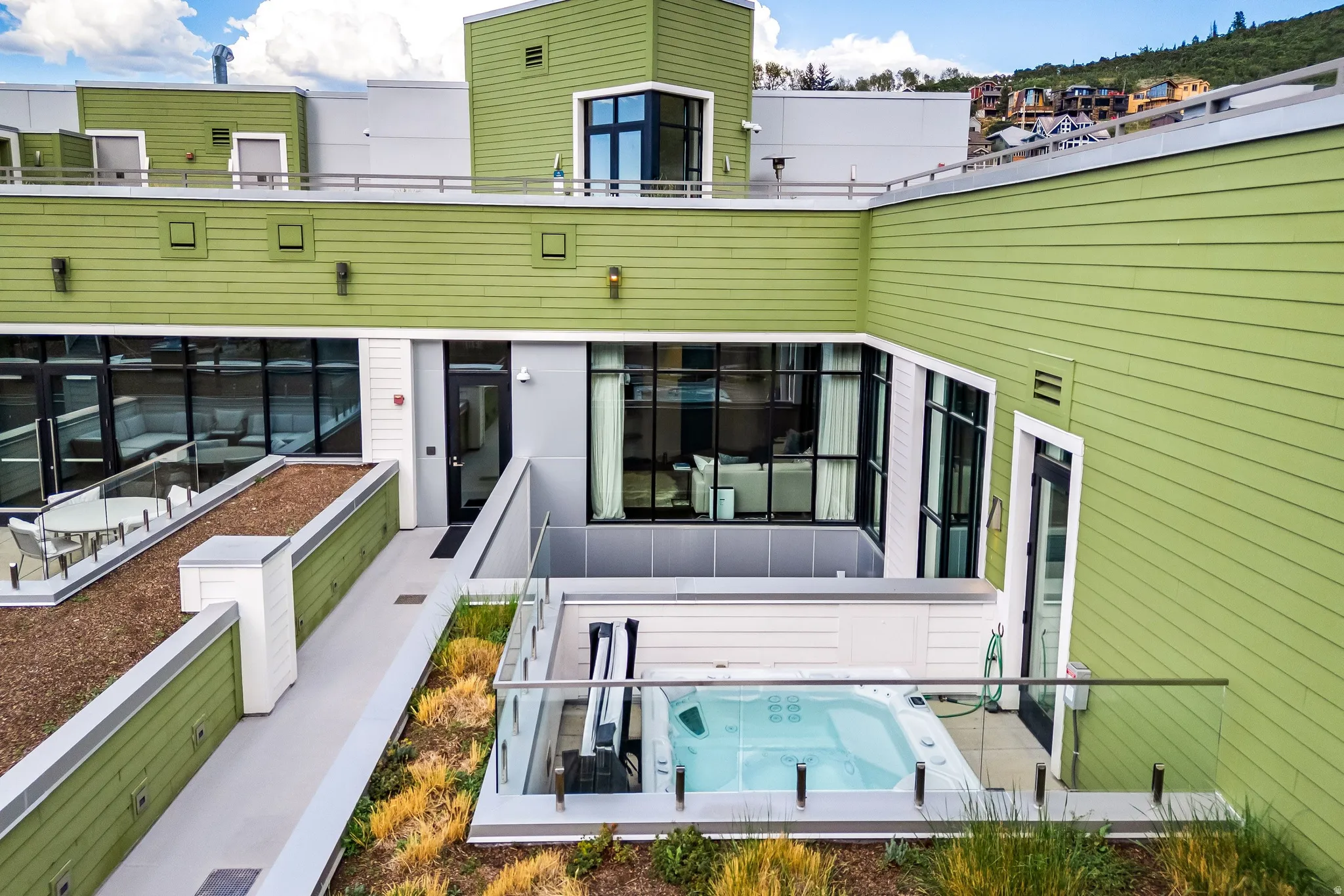 Rooftop terrace featuring a hot tub, glass railings, and direct access to indoor living spaces