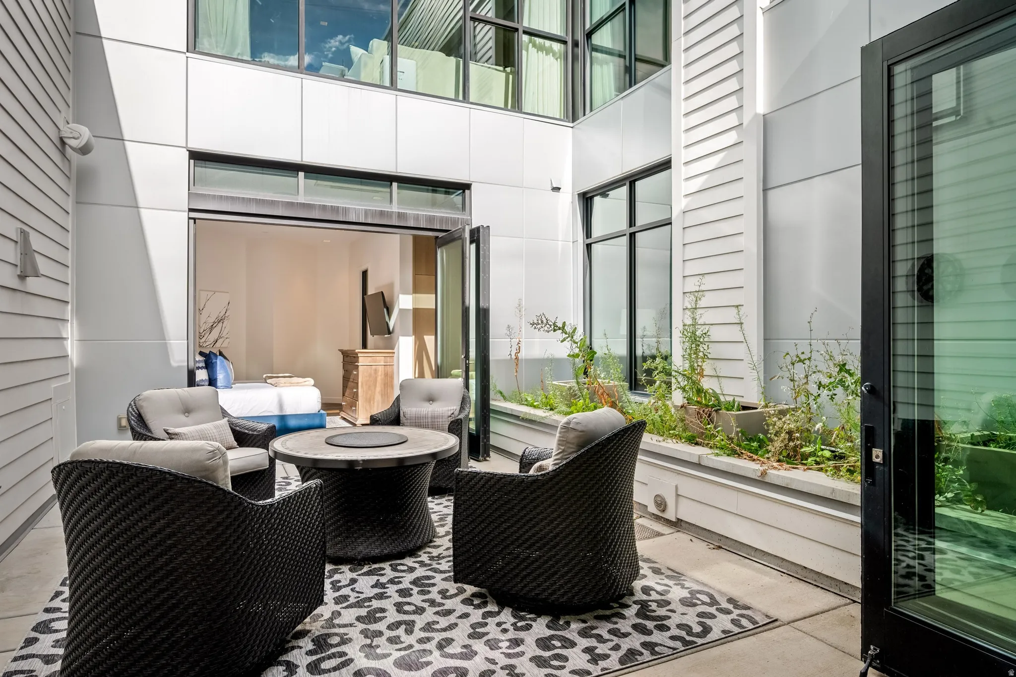 Private outdoor patio with concrete flooring, integrated planter box, and a folding glass door system